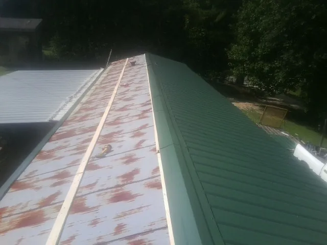 Old rusted panels beside newly installed green metal roofing — Wind Damage Roof Repair by Roofing Brothers in Gladstone