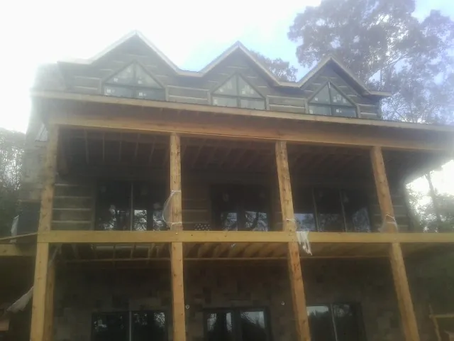 Dormers and porch framing on a large log home under construction — Roof Coating work by our crew in Gladstone